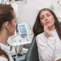 Attractive young woman having toothache, visiting dentist